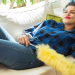 woman lying on couch with feather duster